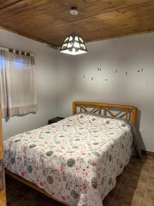 a bedroom with a bed with a floral bedspread at Cabañas bola 8 in Barreal +29 photos