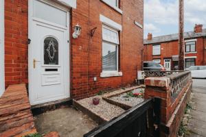 a brick house with a white door and a garden at Denton Luxury Home - Sleep 8 - Speedy Wi-Fi - Free On-Site Parking in Denton