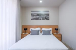 a bedroom with a large white bed with two lamps at CasAmalia 54 in Viana do Castelo