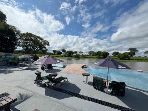 a swimming pool with chairs and umbrellas next to a lake at Kwati Villa in Parintins +20 photos
