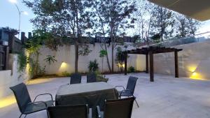 a patio with a table and chairs and a woodenilion at Spacious Abdoun 2BR with private garden & pool access in Amman