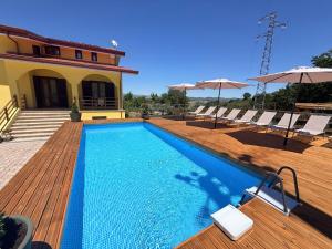 a swimming pool on a wooden deck with chairs and umbrellas at Relais Green Paradise in Apice