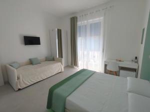 a white bedroom with a bed and a couch at Le Cromie di Amelie in Ceglie Messapica