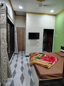 a bedroom with a bed and a flat screen tv at Ganesh Cottage in Matheran