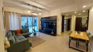 a living room with a couch and a tv at Spacious Abdoun 2BR with private garden & pool access in Amman