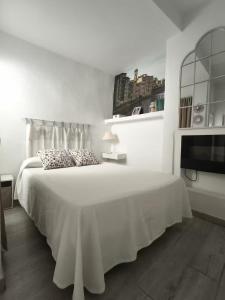 a white bedroom with a bed and a tv at Apartamentos Teresita in Badajoz
