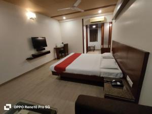 a hotel room with a bed and a tv at Hotel Ikon in Hubli +4 photos