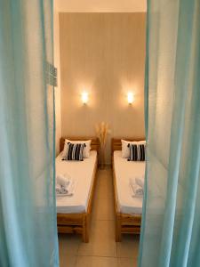two beds in a room with blue curtains at Beachfront Paradise in Leptokarya +9 photos