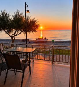 a sunset over the ocean with a table and chairs at Beachfront Paradise in Leptokarya