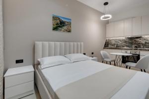 a bedroom with a white bed and a kitchen at Swimming Pool - Marko Studios Berat in Berat +37 photos
