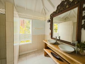 a bathroom with two sinks and a mirror at Fond Doux Eco Resort in Soufrière +37 photos