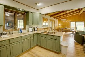 a kitchen with green cabinets and a living room at Mountain Views + BBQs: Updated Cody Cabin in Cody