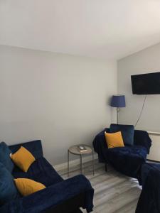 a living room with two blue couches and a table at The Reading three bedroom chalet with gardens, suitable for contractors in Reading