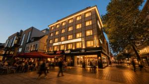 a building on a street with people walking in front of it at Locals Stadthotel Bielefeld in Bielefeld