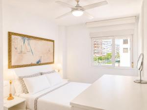 a white bedroom with a bed and a window at Seaside Apartment Retreat in Benicàssim