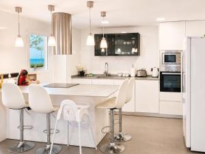 a white kitchen with white chairs and a counter at Seaside Apartment Retreat in Benicàssim