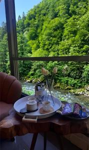 a table with a plate of food with a view of a river at Villa Del Rio Karadeniz River Palace Ayder in Çamlıhemşin +8 photos
