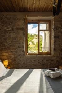 a bedroom with a bed and a window at PETRASTERO Mountain Retreat-Agrafa Evrytania Greece in Vérnikon