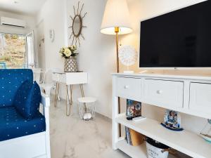 a living room with a tv and a blue chair at Siviri Sea & Forest-Cozy Apartment with Garden & Nature Views in Siviri