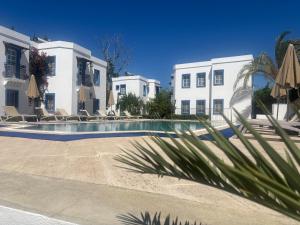 a swimming pool in front of two white buildings at Ege Apartments in Yalıkavak
