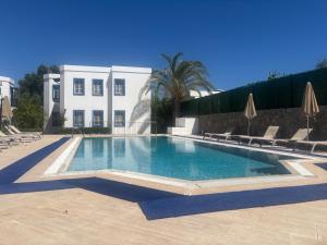 a swimming pool in front of a white building at Ege Apartments in Yalıkavak