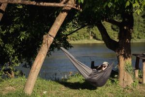 a man laying in a hammock next to a river at Riverside Home Laura in Karlovac