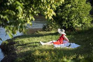a woman sitting on the grass next to a river at Riverside Home Laura in Karlovac