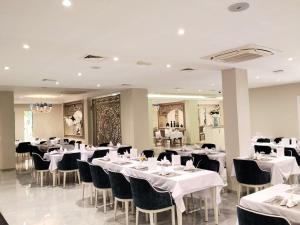 a dining room with white tables and black chairs at Hotel Maamoun in Gafsa