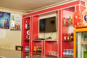 a room with a red wall with bottles of alcohol at Morika Hotel in Mbarara