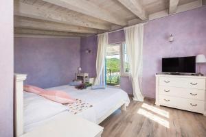 a purple bedroom with two beds and a television at Trasorka House in Veli Lošinj