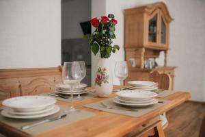 a table with plates and glasses and a vase with roses at Fewo-Welz in Bad Kissingen