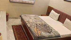 a bed with a blanket on top of it at Abhilashaa Inn in Pachmarhī