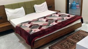 a bed with a quilt on it in a room at Abhilashaa Inn in Pachmarhī