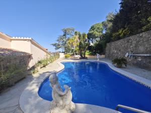 a swimming pool with a statue next to a house at Villa Serra Brava mt Gemeinschatspool, 3 Apartments in Lloret de Mar