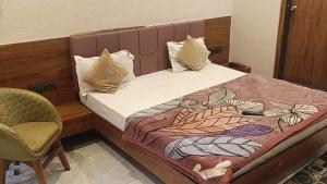a bedroom with a bed and a chair at Abhilashaa Inn in Pachmarhī