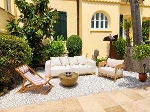 a patio with a couch and two chairs and a table at La Garoupe-Gardiole Boutique Hotel in Antibes