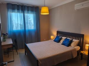 a bedroom with a bed and a window with blue curtains at Michelle Mediterranean Suites in Meneou