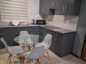 a kitchen with a glass table and white chairs at Trendy Tranquility in Secunda