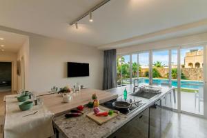 a kitchen with a counter with a sink and a tv at Wellness Hygge Modern Gozitan Apartment - Happy Rentals in Taʼ Sardina