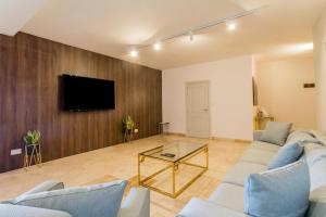 a living room with a couch and a tv on a wall at Wellness Hygge Modern Gozitan Apartment - Happy Rentals in Taʼ Sardina +28 photos