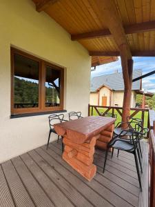 a wooden table and chairs on a deck at Domki u Gretka in Lutowiska