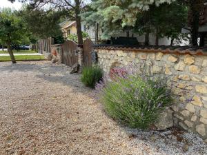 a stone retaining wall with a fence and flowers at Páfrányház in Fertőd