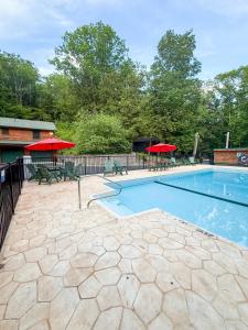 a swimming pool with red umbrellas and tables and chairs at Northern Acres in Lake George