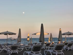 a group of chairs and umbrellas on a beach at Michelle Mediterranean Suites in Meneou