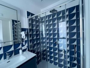 a blue and white bathroom with a shower and a sink at Metasuites Beach in Meta