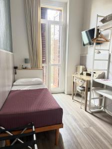a bedroom with a bed and a desk and a window at Hotel Malta in Milan
