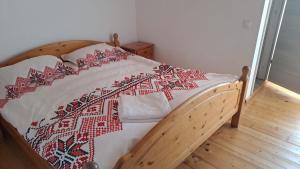 a bed with a red and white quilt on it at Casa Cătălin-Puntea Craiului in Şirnea