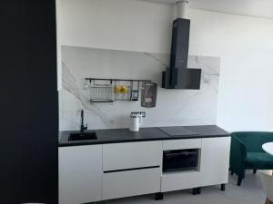 a kitchen with white cabinets and a black counter top at Itown Apartments in Odesa