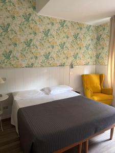 a bedroom with a bed and a yellow chair at Hotel Malta in Milan