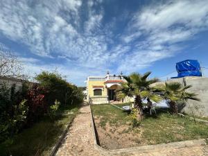 a small house with a palm tree in the yard at Villa Bingo & Piscine in El Jadida